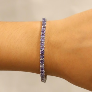 Op de afbeelding: Een zilveren tennisarmband met paarse edelstenen.