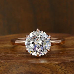 Può includere: Un anello di fidanzamento in oro rosa con un grande diamante rotondo e chiaro.