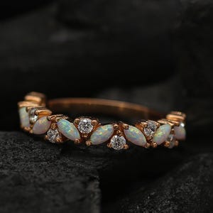 Può includere: Un anello a fascia in oro rosa con un design delicato con dettagli in opale bianco e diamanti.