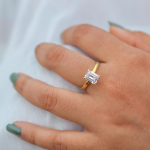 May include: A gold ring with a large, clear, emerald-cut gemstone.