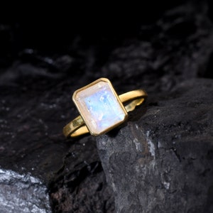 May include: A gold ring with a large, rectangular, iridescent moonstone.