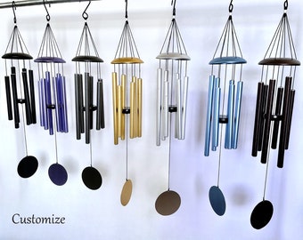 Könnte beinhalten: Eine Sammlung von Windspielen in verschiedenen Farben, darunter Schwarz, Lila, Gold, Silber, Blau und Braun. Jedes Windspiel hat eine kreisförmige Oberseite und einen passenden kreisförmigen oder ovalen Windfänger. Das Wort "Customize" steht unten.