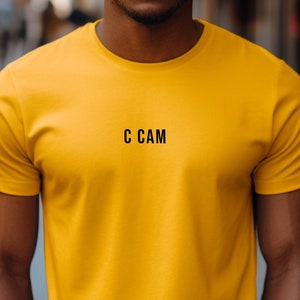 May include: A yellow t-shirt with the text "C CAM" printed on the front.