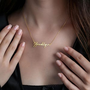 May include: A gold necklace with the name "Brooklynn" written in cursive script.