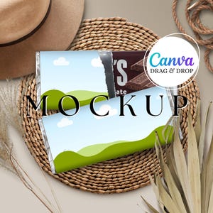May include: A mockup featuring a chocolate bar with a landscape design, set on a woven mat. The bar's wrapper displays a blue sky, green hills, and white clouds. The word "MOCKUP" is prominently displayed. A hat, rope, and dried plants are also visible.