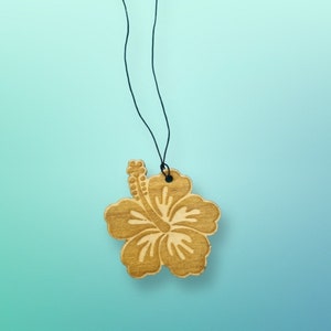 May include: A wooden car air freshener shaped like a hibiscus flower with a black string for hanging.