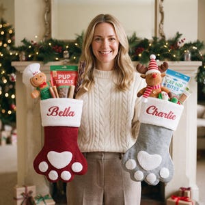 May include: Two felt Christmas stockings shaped like animal paws, one red with the name Bella and one gray with the name Charlie. Both feature white cuffs and paw pads. They are filled with various pet treats and plush toys, including a gingerbread chef and a reindeer.