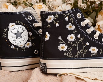 Puede incluir: Par de zapatillas Converse Chuck Taylor All Star de caña alta negras con bordado floral blanco. Las zapatillas tienen cordones blancos, suela blanca y el parche del logo Converse All Star.