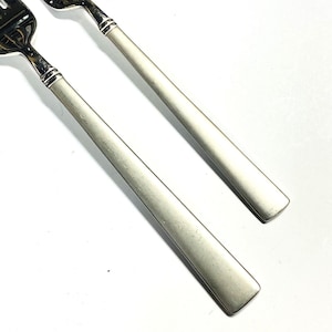 以下が含まれることがあります： シンプルなデザインの、ブラシ仕上げの銀製のフォーク2本