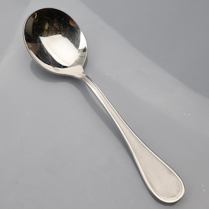 Puede incluir: Una cuchara de sopa de plata con un cuenco redondeado y un mango largo y delgado.