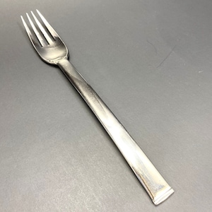 May include: A silver fork with a long, slender handle. The fork has four tines and a smooth, polished finish.