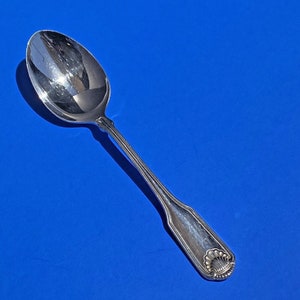 May include: A silver spoon with a decorative handle. The handle has a raised design of a shell.