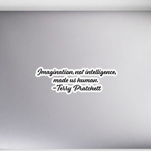 May include: A laptop computer with a sticker that reads "Imagination, not intelligence, made us human. -Terry Pratchett"
