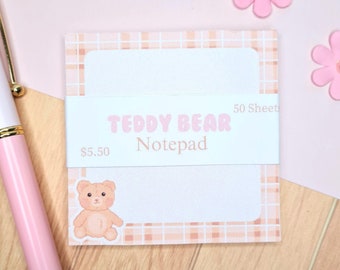 Puede incluir: Un bloc de notas a cuadros rosa y marrón con una ilustración de un osito de peluche y el texto "Teddy Bear Notepad 50 Sheet $5.50".