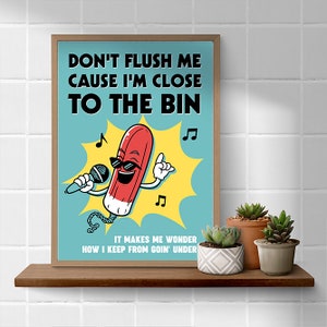May include: A framed poster featuring a cartoon tampon with sunglasses and a microphone, set against a light blue backdrop. Text on the poster reads "DON'T FLUSH ME CAUSE I'M CLOSE TO THE BIN" and "IT MAKES ME WONDER HOW I KEEP FROM GOIN' UNDER".