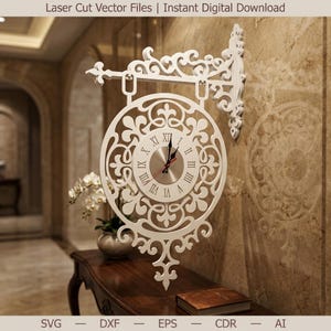 May include: A white, laser-cut wall clock with an ornate, symmetrical design. The clock face is silver with black Roman numerals and black hands. The clock is mounted on a wall with a decorative bracket. The text "Laser Cut Vector Files | Instant Digital Download" is at the top.