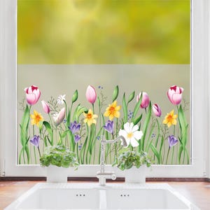 Könnte beinhalten: Ein Fenster mit einer mattierten Glasscheibe, die ein farbenfrohes Blumenmuster zeigt. Das Muster umfasst rosa Tulpen, gelbe Narzissen, lila Krokusse und weiße Kosmeen. Die Blumen sind in einer Reihe am unteren Rand der Scheibe angeordnet, mit grünen Stielen und Blättern, die nach oben ragen.