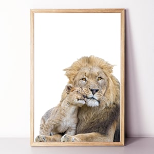 Può includere: Una stampa incorniciata con un leone e un cucciolo di leone. Il leone adulto ha una criniera folta ed è posizionato accanto al cucciolo, che si accoccola sul suo viso. La stampa è in una cornice di legno chiaro.