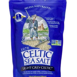 Peut inclure: Un sac bleu de sel de mer celtique. Le sac pr&eacute;sente une illustration d'une personne ratissant du sel, avec le texte "Celtic Sea Salt" et "Light Grey Celtic". Le poids net est de 454 g.