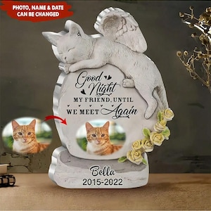 Puede incluir: Una placa conmemorativa color piedra con un gato esculpido con alas de ángel. La placa muestra el texto Good Night MY FRIEND, UNTIL WE MEET Again, una foto circular de un gato naranja, el nombre Bella y los años 2015-2022.