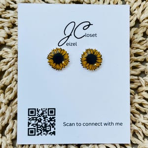 May include: A pair of sunflower stud earrings with black centers and yellow petals, displayed on a white card with the text "JC closet eizel" and a QR code that says "Scan to connect with me".