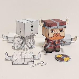 May include: Papercraft model of a Viking warrior with a red and brown helmet, red and brown armour, a red beard, and a shield. The model is made of paper and is ready to be assembled.