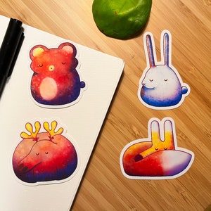 May include: Four colourful animal stickers with watercolour-like designs. A red bear, a white rabbit, a red deer, and a red fox are all curled up sleeping.