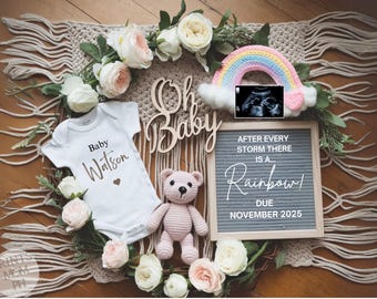 Pode incluir: Um anúncio de revelação de gênero com um macacão branco que diz "Baby Watson" e um quadro de letras que diz "Depois de cada tempestade há um... Arco-íris! Previsão para novembro de 2025".