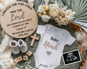 May include: A wooden sign with the text "I prayed for this child and the Lord has granted me what I asked of him. 1 Samuel 1:27. Our blessing is due on April 2025." A white onesie with the text "Baby Noah" and a gray heart. A wooden cross, a pair of white baby shoes, and a black and white ultrasound image.