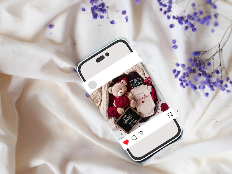 K&ouml;nnte beinhalten: Ein Smartphone-Bildschirm zeigt ein Foto eines Teddyb&auml;ren, der einen roten Rosenstrau&szlig; h&auml;lt, einen Baby-Strampler mit dem Text "Unser kleiner Valentinstag" und ein schwarzes Schild mit der Aufschrift "Baby Smith, Unser kleiner Valentinstag, 2023". Das Foto ist mit einem wei&szlig;en Rahmen versehen und hat ein rotes Herz, ein Kommentarsymbol und ein Freigabesymbol.