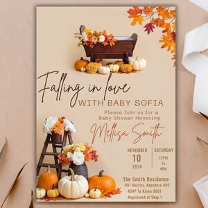 May include: A baby shower invitation with a fall theme. The invitation features a wooden cradle with pumpkins and fall leaves. The text reads "Falling in love with Baby Sofia".