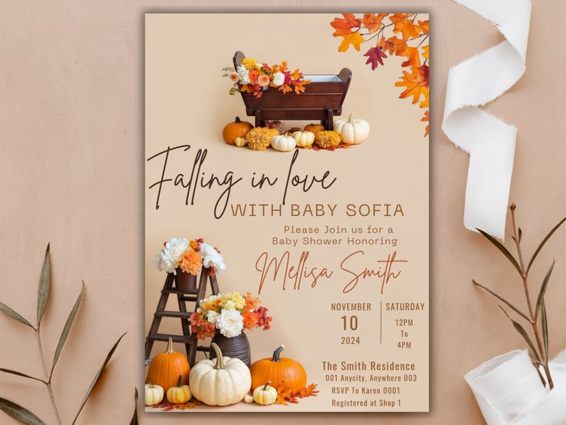 May include: A baby shower invitation with a fall theme. The invitation features a wooden cradle with pumpkins and fall leaves. The text reads "Falling in love with Baby Sofia".