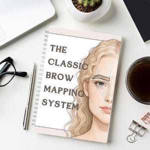 Op de afbeelding: Een spiraalgebonden notitieboek met de tekst "THE CLASSIC BROW MAPPING SYSTEM" en een illustratie van een vrouwengezicht. Het notitieboek ligt op een wit oppervlak met een pen, een bril en een kopje koffie.
