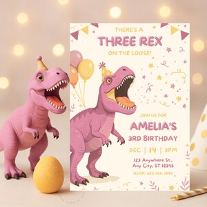 Könnte beinhalten: Eine rosa Tyrannosaurus Rex-Figur neben einer Geburtstagseinladung. Die Einladung lautet "There's a Three Rex on the Loose!" und enthält Party-Details für Amelias 3. Geburtstag.