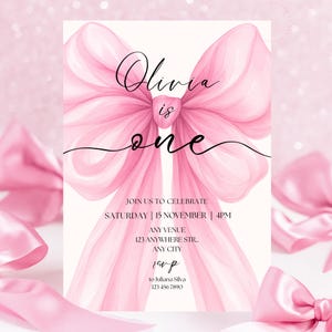 May include: A pink watercolour invitation for a first birthday. The design features a large pink bow and the words "Olivia is one." Additional text includes party details: date, time, venue, and RSVP information.
