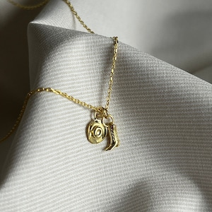 May include: A gold chain necklace with a charm of a cowboy hat and a boot.
