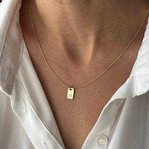 May include: A gold chain necklace with a small rectangular pendant featuring a pumpkin design.