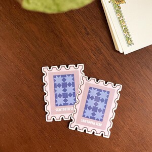 May include: Two pink and brown patterned stickers with a blue star design. The stickers have a white border and the text "Sawtooth Star" is printed on the bottom.