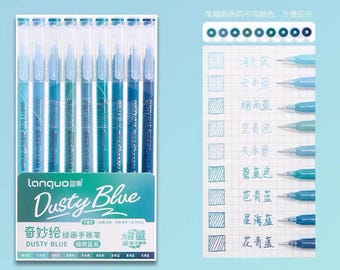 May include: A set of blue gel pens in a box labeled "Dusty Blue." The pens are in various shades of blue and green. A color chart shows the different ink colors, including "Sky Blue" and "Rainy Blue."