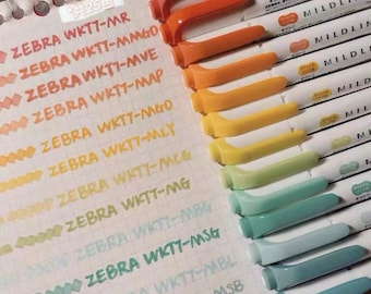 May include: A collection of Zebra Mildliner highlighters in various pastel colors. The image shows the pens with their caps and the corresponding ink swatches on a grid paper. The text on the pens and paper is visible.