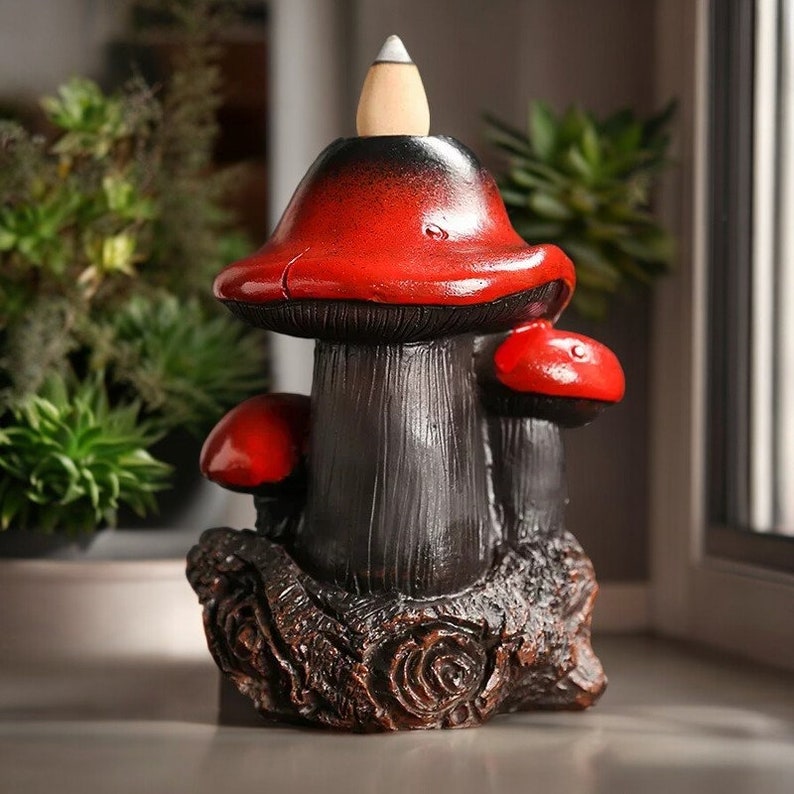 May include: A black and red ceramic incense burner shaped like a mushroom with a cone-shaped incense holder on top.