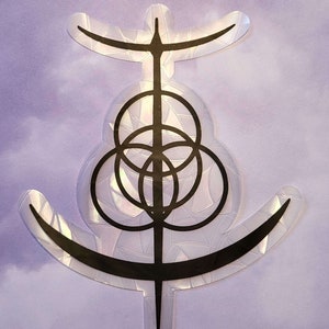 Könnte beinhalten: Ein schwarz-weißer Aufkleber mit einem geometrischen Design. Das Design zeigt einen Kreis mit einem Kreuz darin, umgeben von drei kleineren Kreisen. Der Aufkleber befindet sich auf einem violetten Hintergrund.