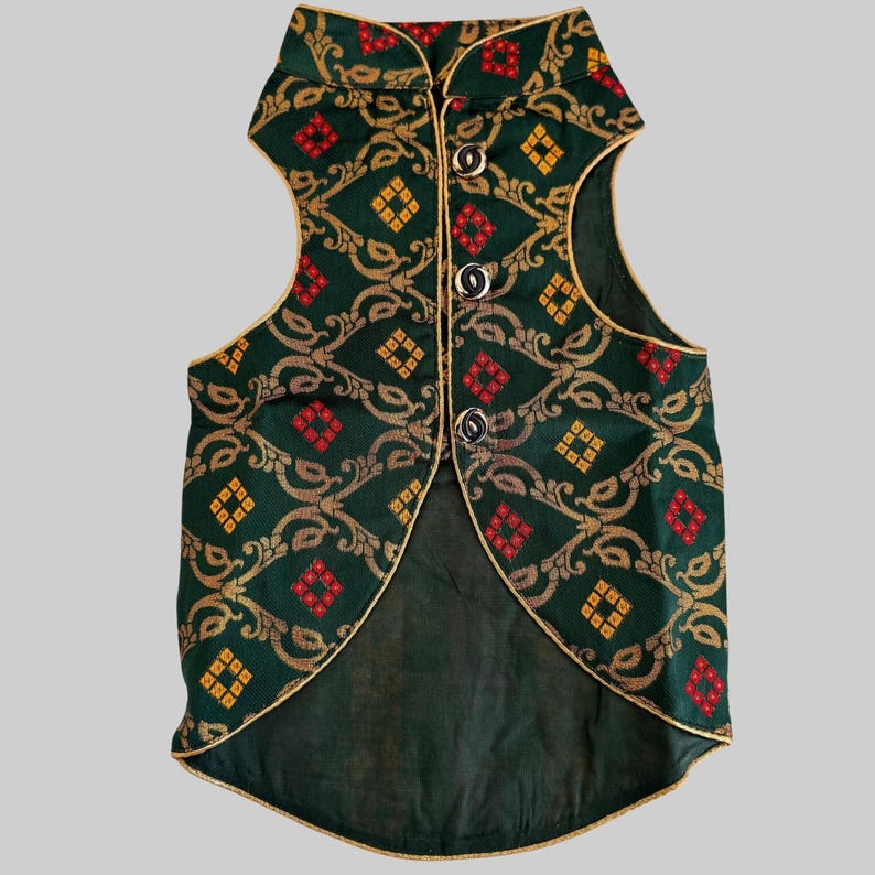 May include: A sleeveless waistcoat featuring a dark green fabric with a repeating gold scrollwork pattern and small red and yellow diamond accents. The garment has a high collar, gold piping along the edges, and three silver-toned buttons down the front.