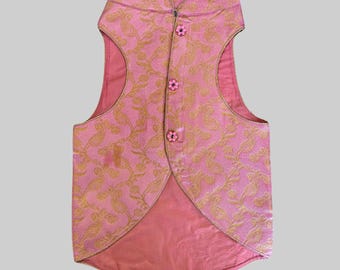 May include: A pink sleeveless vest with a gold floral pattern and pink buttons. The vest has a mandarin collar and a pointed hem.