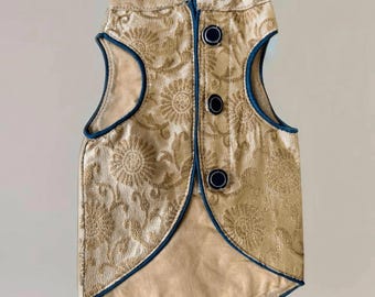 May include: A gold vest with a floral pattern and blue trim. The vest has a mandarin collar and three buttons down the front.