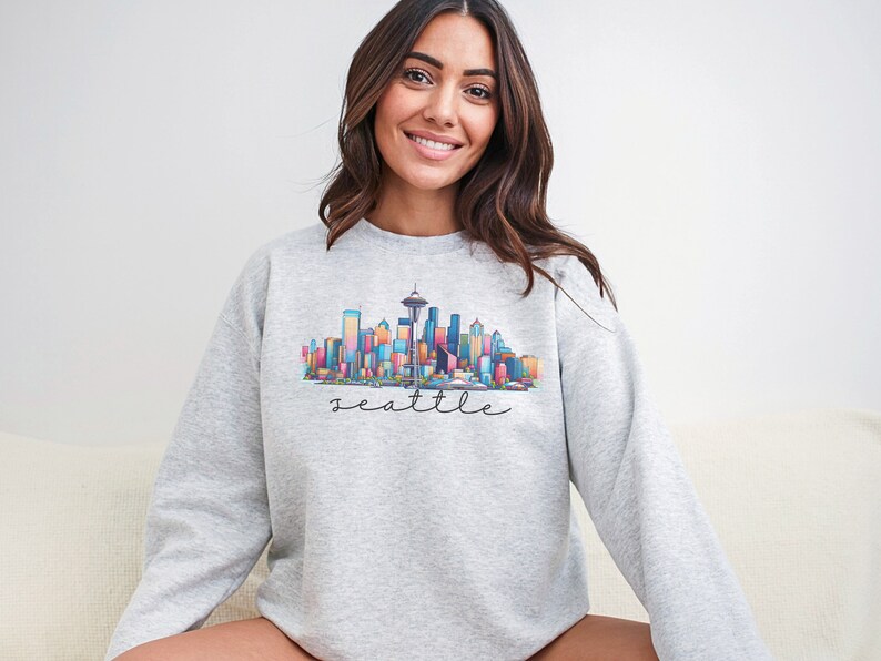 A Seattle sweatshirt with a colorful rendition of the city's skyline and the name Seattle in text. Available as a crewneck sweatshirt or hoodie.