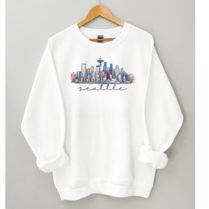 A Seattle sweatshirt with a colorful rendition of the city's skyline and the name Seattle in text. Available as a crewneck sweatshirt or hoodie.