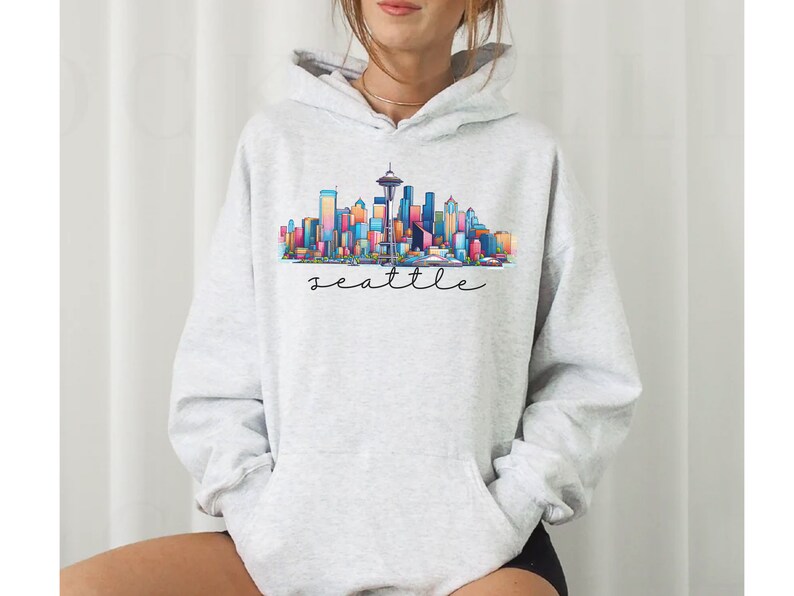 A Seattle sweatshirt with a colorful rendition of the city's skyline and the name Seattle in text. Available as a crewneck sweatshirt or hoodie.