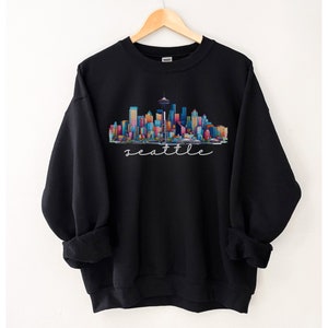 A Seattle sweatshirt with a colorful rendition of the city's skyline and the name Seattle in text. Available as a crewneck sweatshirt or hoodie.