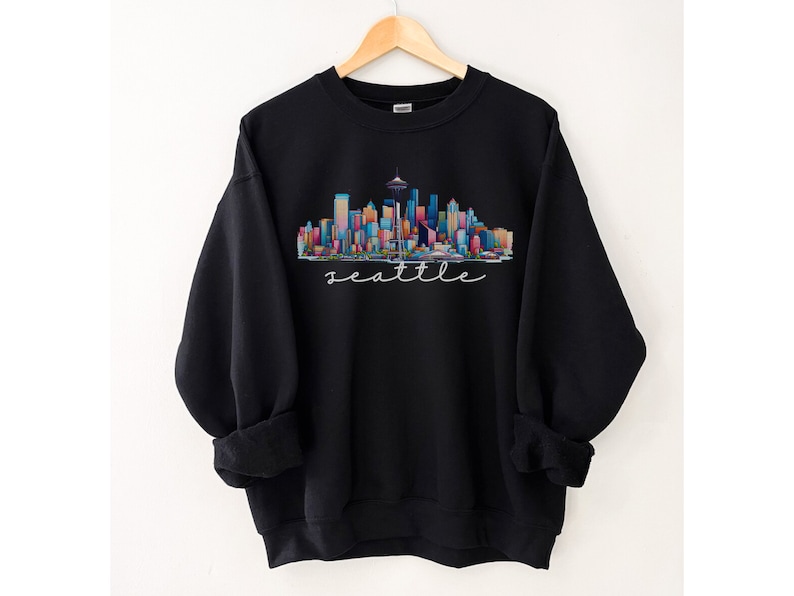 A Seattle sweatshirt with a colorful rendition of the city's skyline and the name Seattle in text. Available as a crewneck sweatshirt or hoodie.